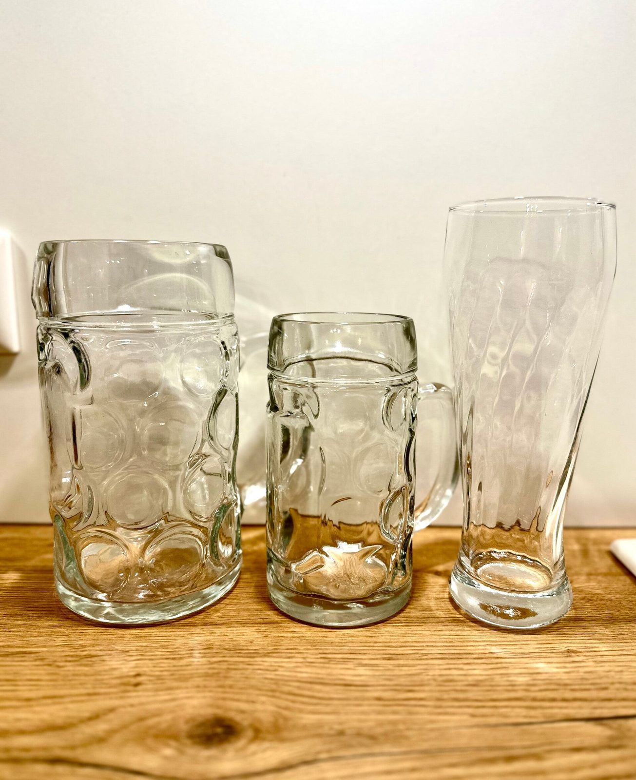 Seidel, Maßkrug und Weizenglas nebeneinander auf einem Holztisch