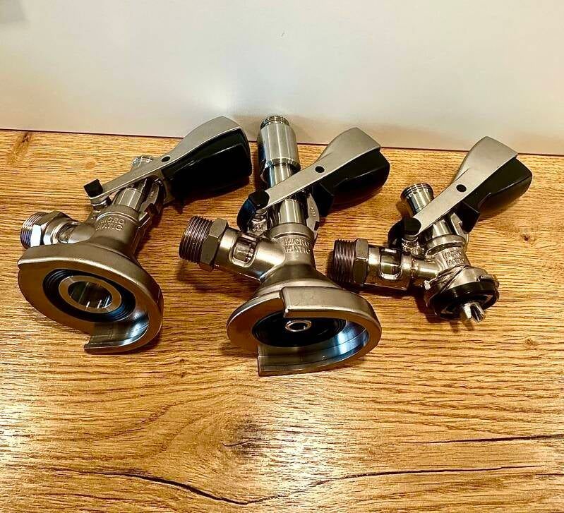 Verschiedene Zapfköpfe (Fittings) auf einem Holztisch